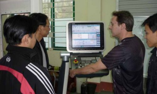 Mr. Andreas Fischer is instructing trainees on operating a Milling CNC machine