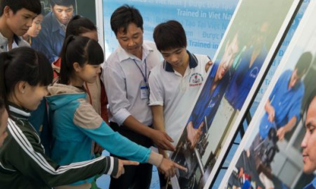 Proud of their jobs – apprentices look at the photo boards in the exhibitionPhotograph: Ralf Baecker/GIZ, Hanoi