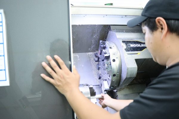 A participant adjusted his workpiece in the CNC lathe chuck to prepare for machine operation.