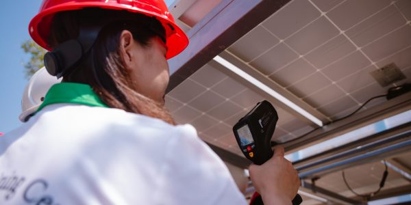 Industry technician practices measuring PV panel’s temperature by using infrared thermometer.