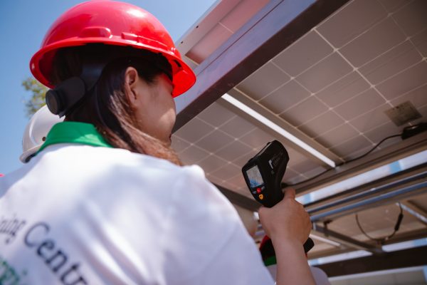 Industry technician practices measuring PV panel’s temperature by using infrared thermometer.